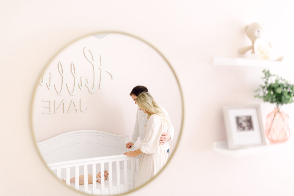 Photo of mother and father standing over crib with newborn baby by Cincinnati newborn photographer