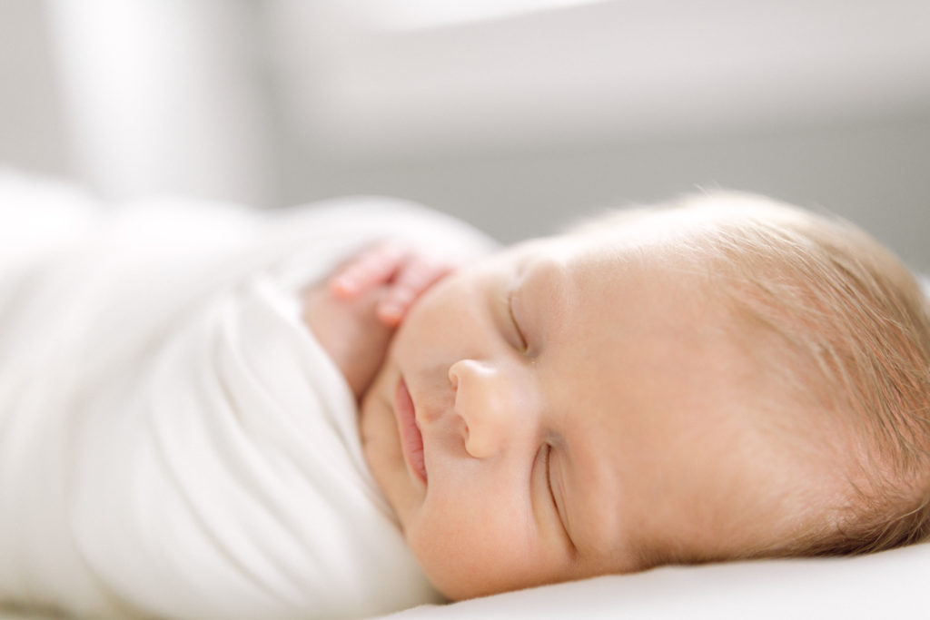 Newborn baby boy swaddled in white blanket taken by Hyde Park Newborn Photographer