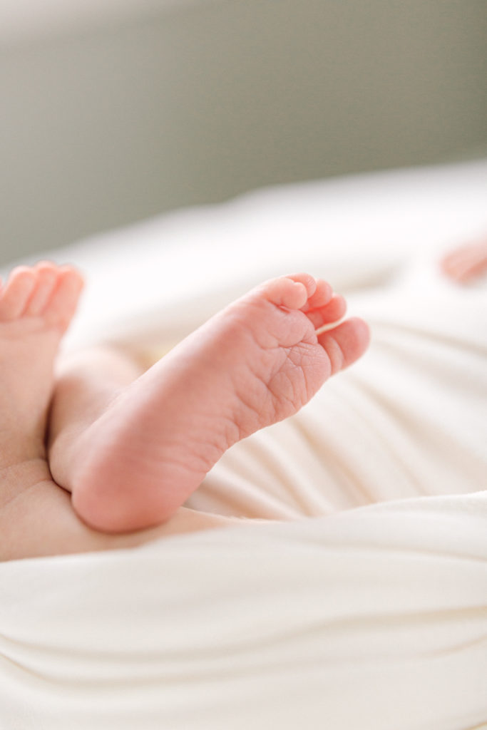 Newborn baby toes peaking out of white blanket taken by Hyde Park Newborn Photographer