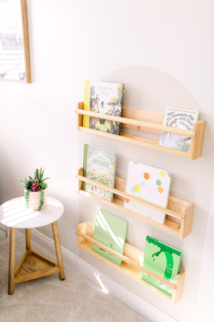 Wooden book shelf holding colorful books in baby's nursery, designed by Cincinnati Interior Designer