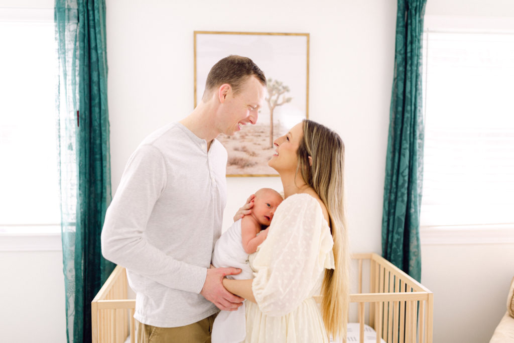 Mother and father holding baby in custom designed nursery by Cincinnati Interior Designer